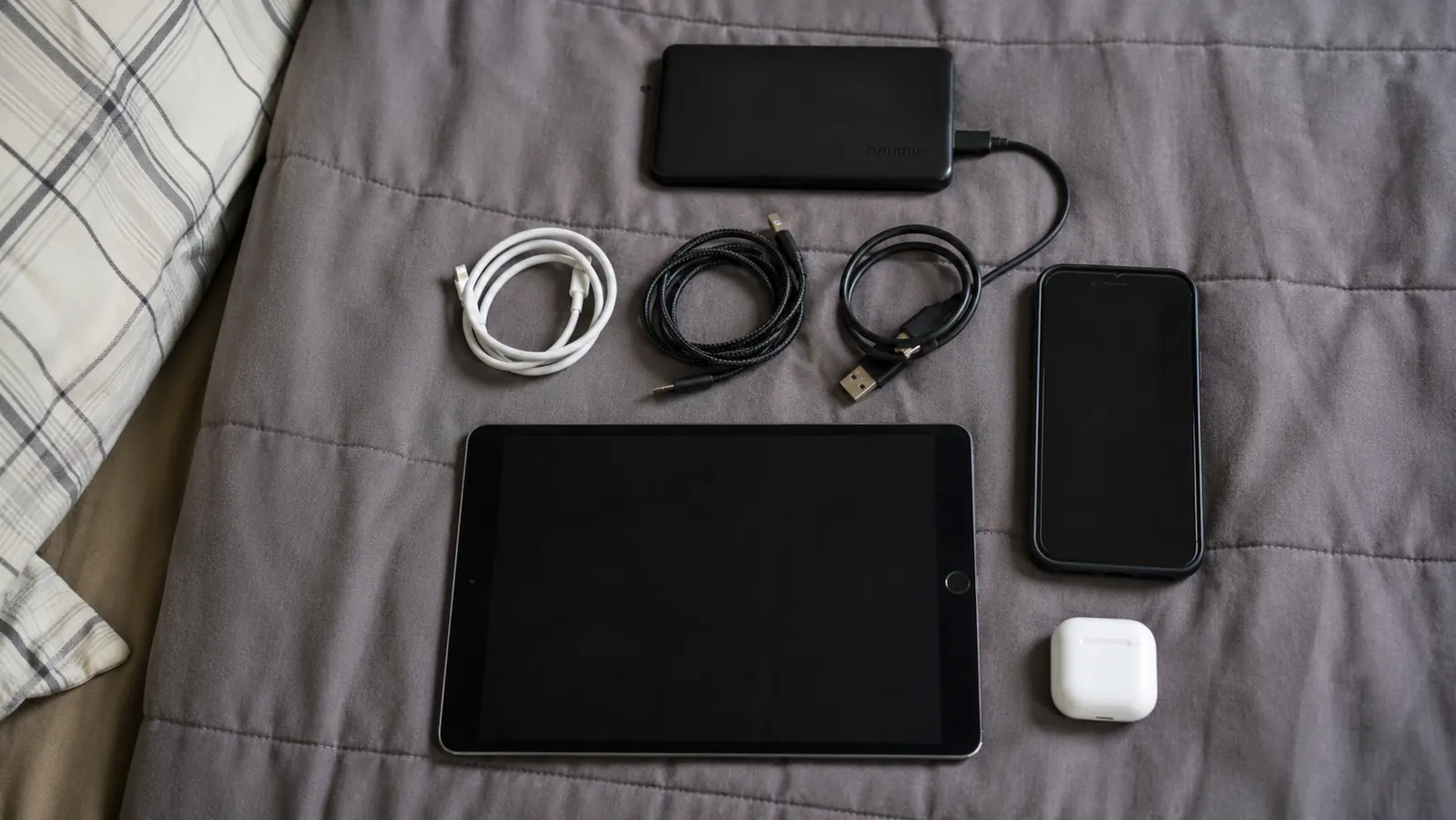 Trucker's gear bag open on a truck bunk showing the power bank, phone, and tablet stacked inside