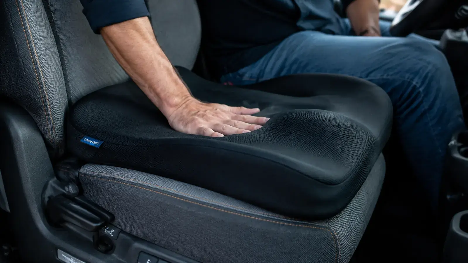Truck driver's hands on the steering wheel, open highway in the windshield, comfortable upright posture